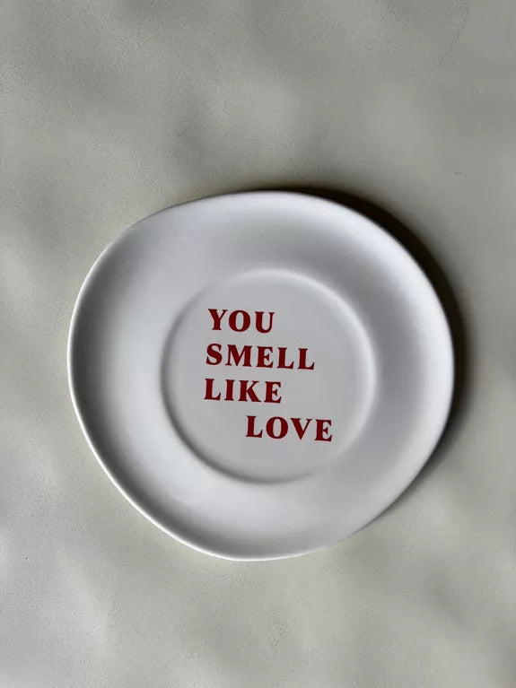 Assiette Tu sens l'amour blanche cassée avec texte rouge « You smell like love », finition brillante, idéale pour dessert ou décoration murale.