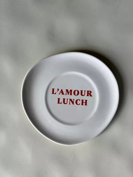 Assiette à dessert Déjeuner L'amour lunch en céramique blanc cassé avec texte rouge au centre, idéale pour une table romantique et moderne.