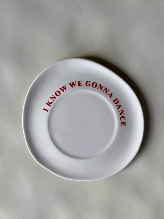Assiette à dessert Je sais qu'on va danser en céramique blanc cassé avec lettrage rouge ludique, idéale pour la décoration ou les repas festifs.