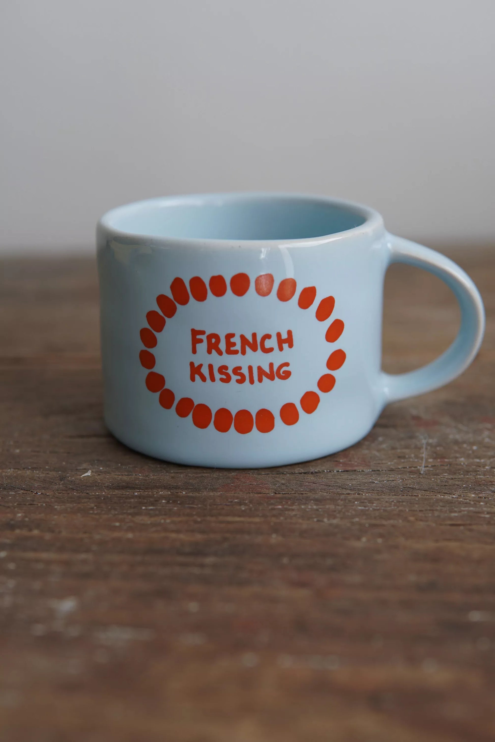 Mug French kiss en céramique bleu clair avec texte rouge 'French Kissing', idéal pour café, compatible micro-ondes et lave-vaisselle.