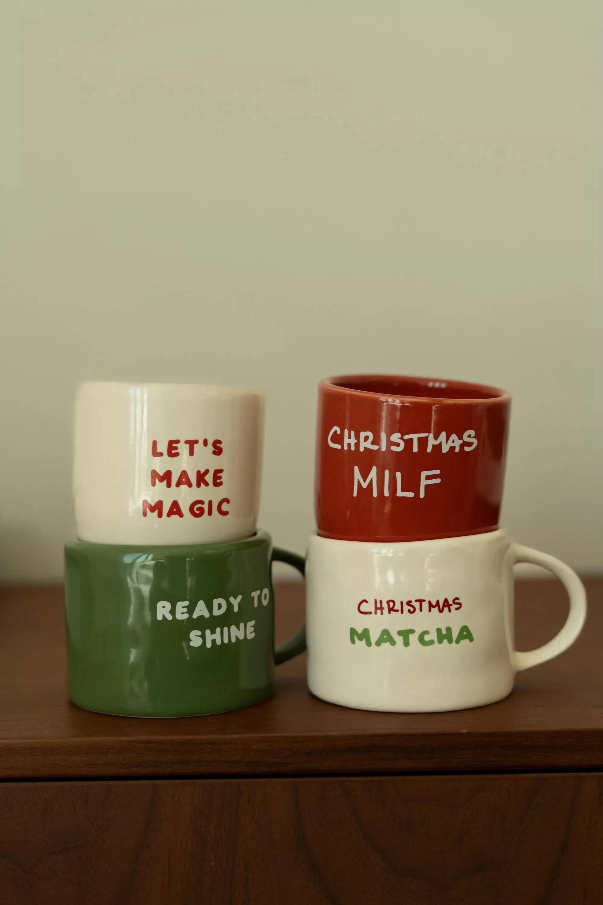 Mug Matcha de Noël en céramique blanche avec inscription 'Christmas Matcha' en rouge et vert, posé sur une surface en cuir vert foncé. Idéal pour boissons festives.